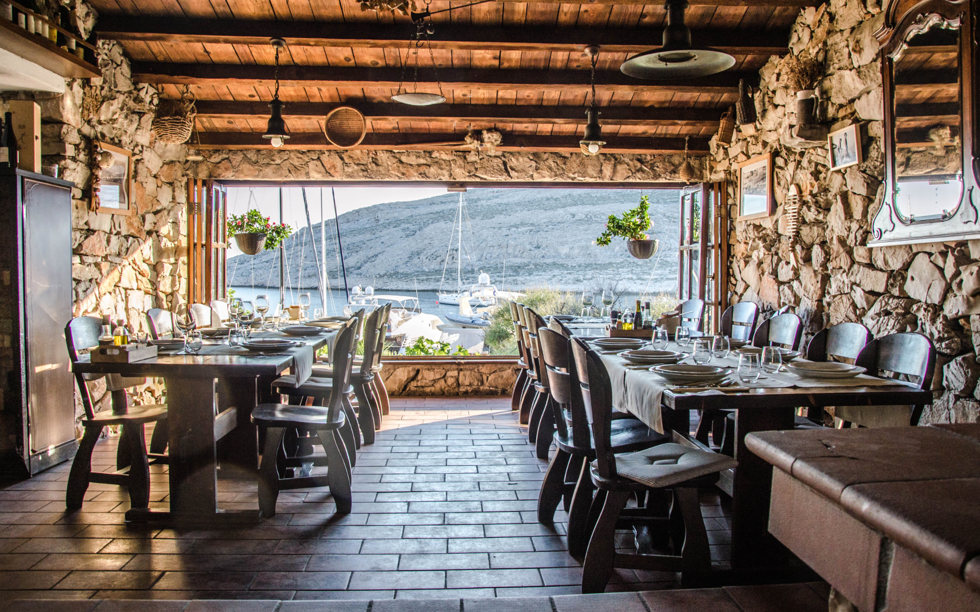 Dining room of Konoba Opat with stone walls, wooden beams and open doors to the sea